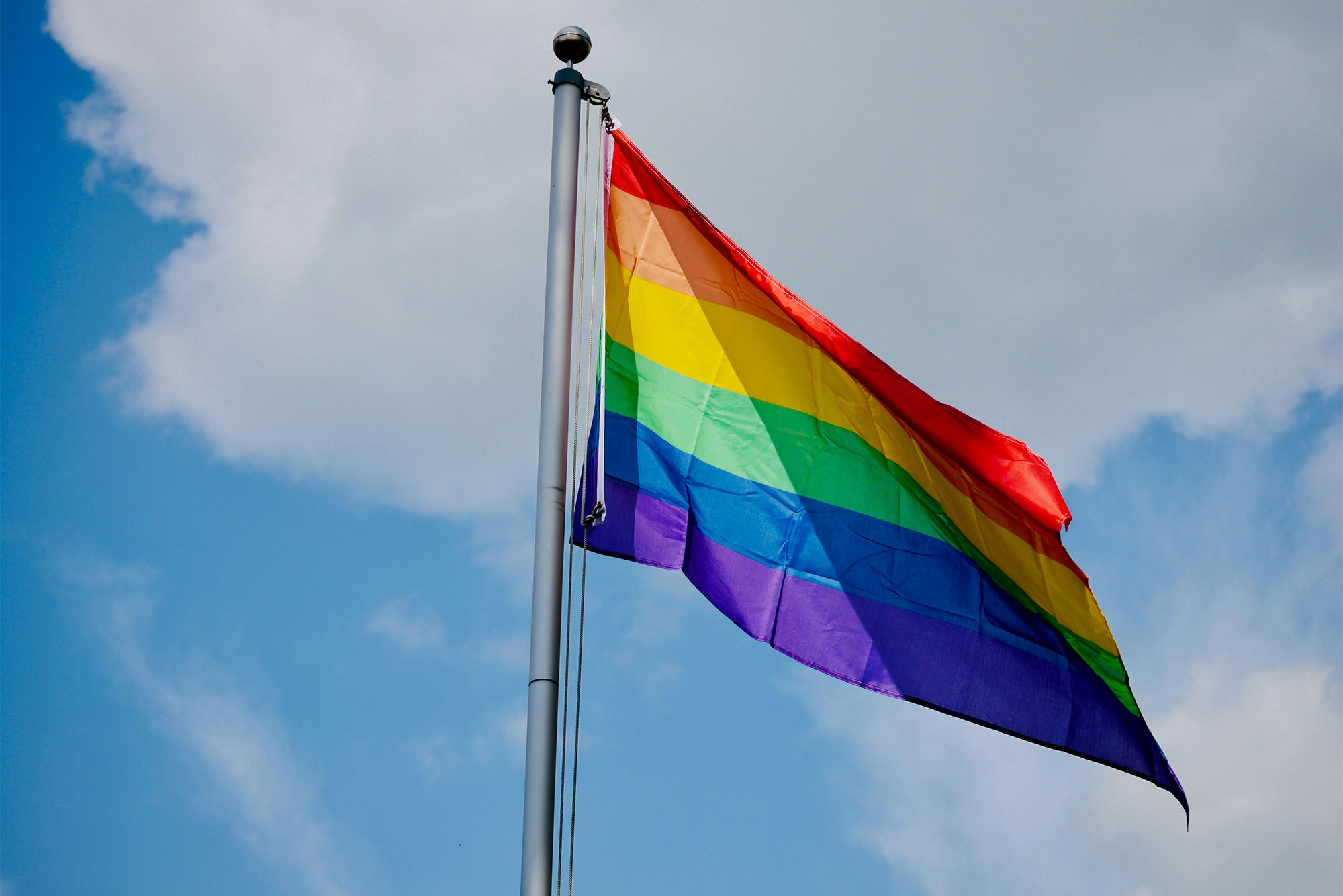 Photo: An LGBT rainbow flag flying on a sunny day