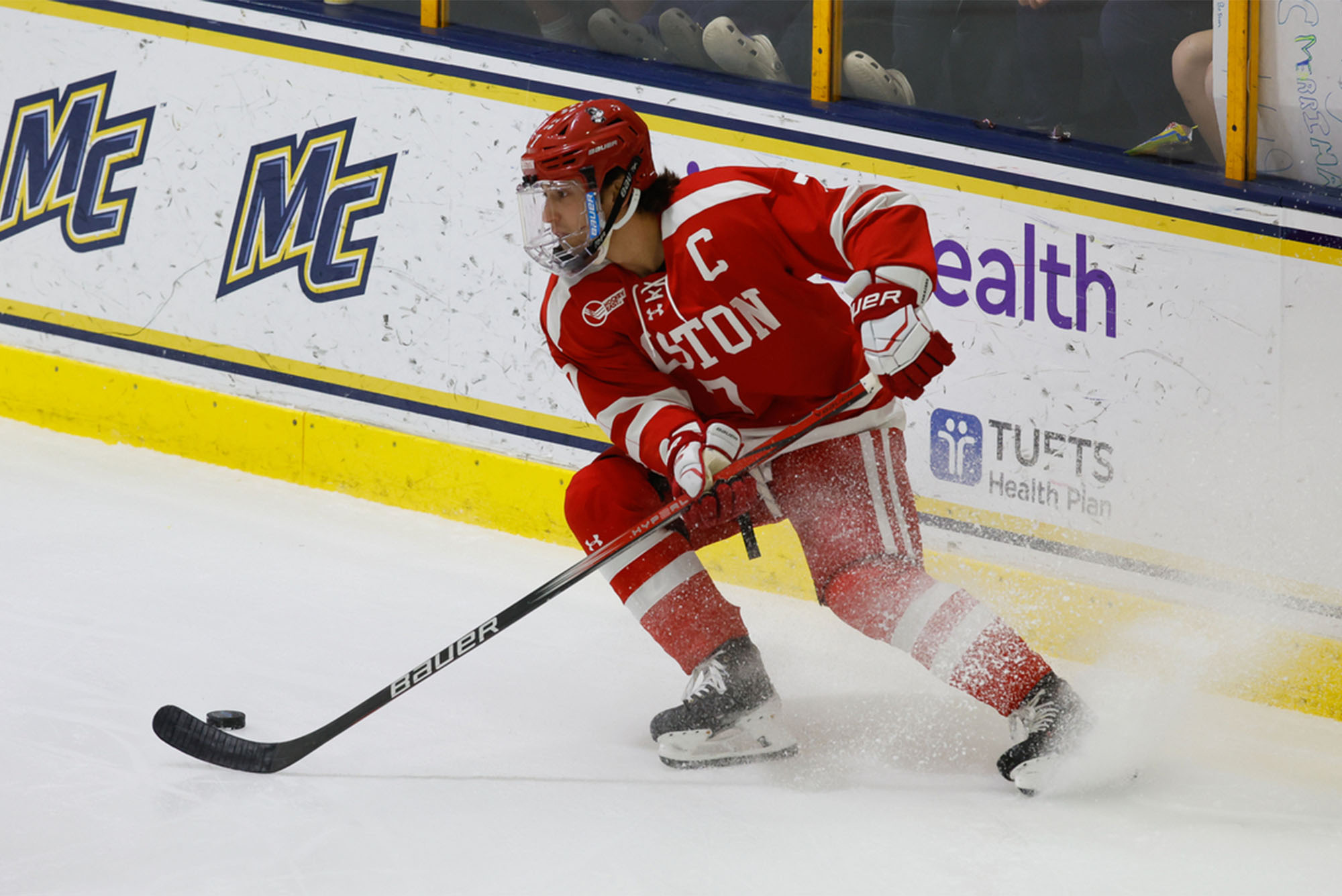 Photo: A college hockey player in a red jersey stops and sends ice flying during a recent game