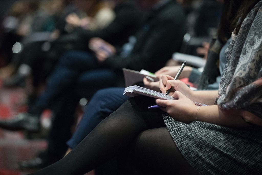 Photo: A woman writing in a small journal at an event