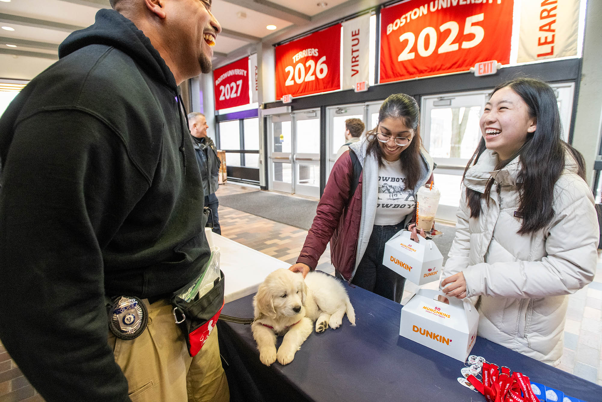 Photo: Patrolmen watch over as BU students pet their new comfort dog, a white, fluffy golden retriever.