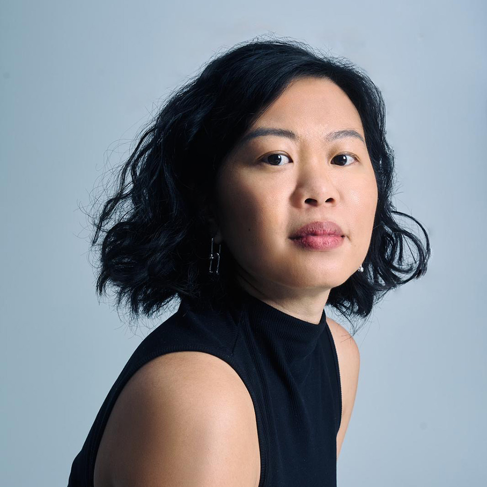 Photo: A young Asian woman, Emily Feng, poses for a photo. She has short black hair, and wears a turtleneck tank.