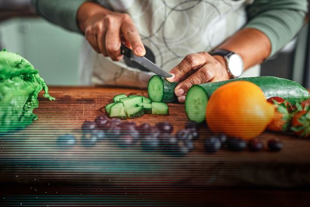 Photo: A stock image of an individual cutting a cucumber with various other rainbow fruits and vegetables on the cutting board. A glitch overlay rest on top of the image.