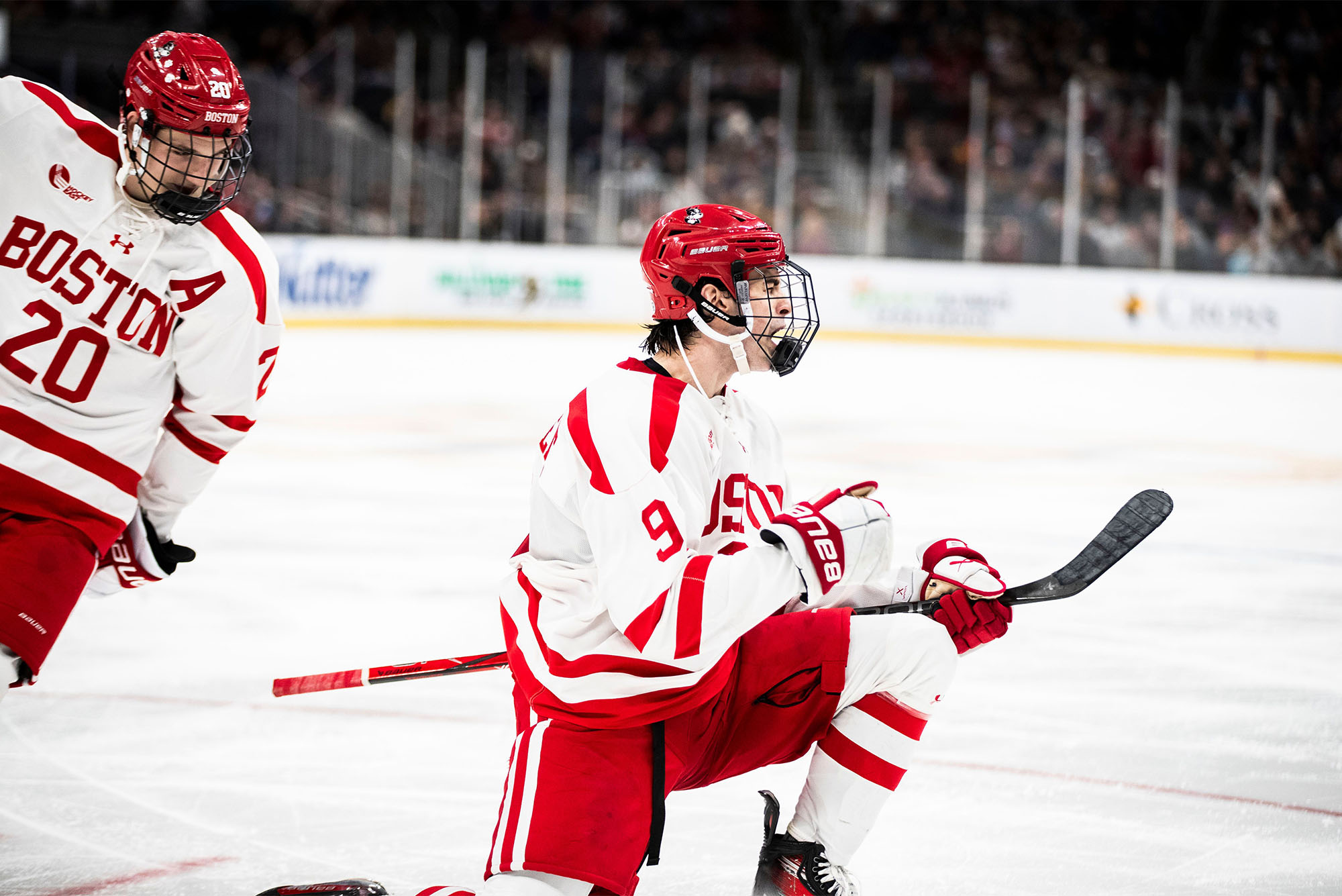 Photo: A BU college hockey player in red and white jersey pumps their fist after scoring a goal