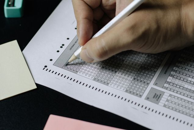 Photo: A hand holding a pencil filling in bubbles on a standardized test