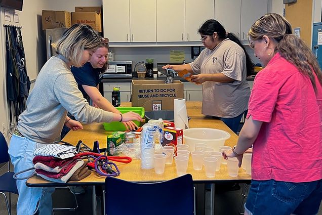 Photo: Multiple people at a table sorting things into cups and storage.