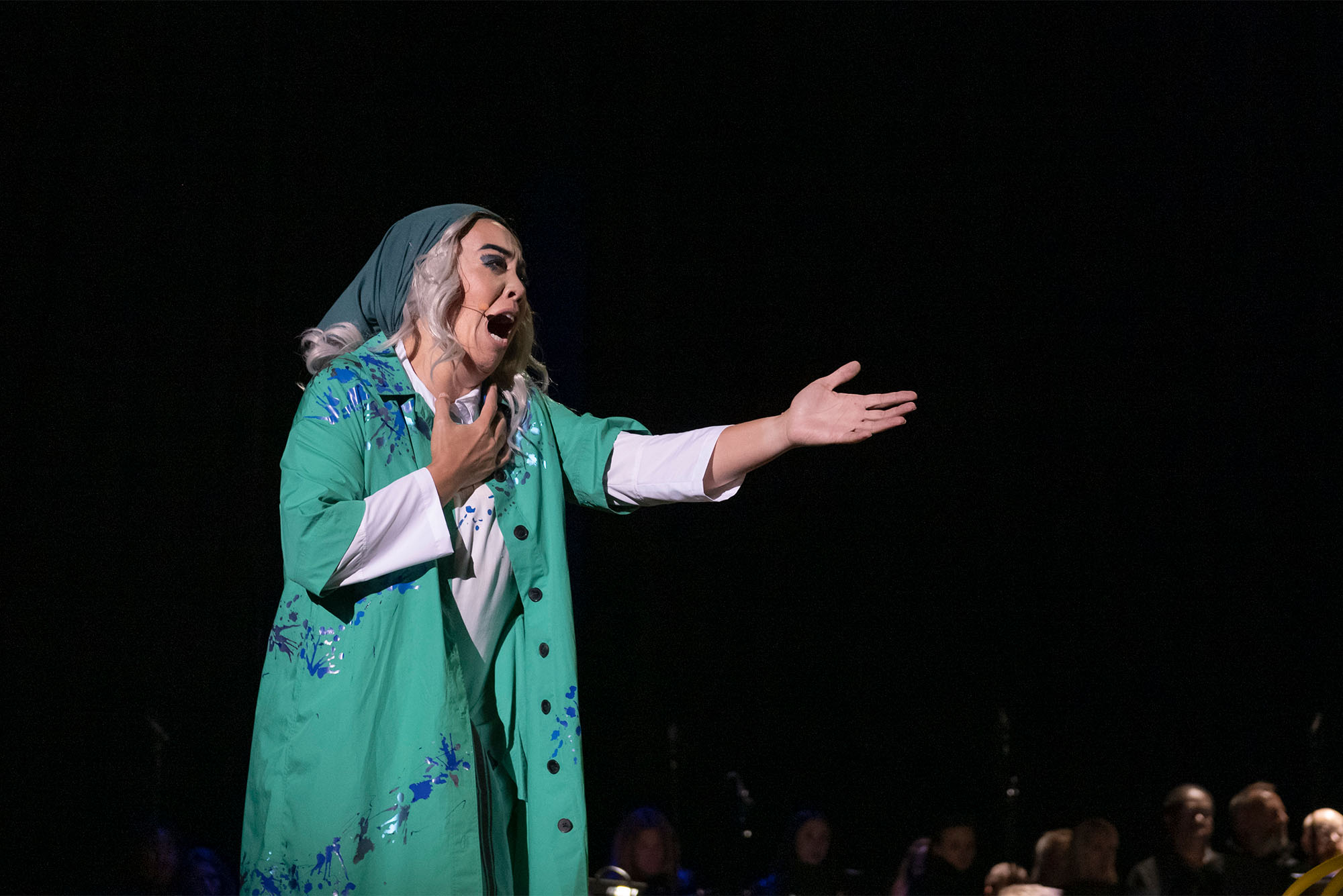 Photo: A woman wearing a hooded veil sings opera in front of a crowd
