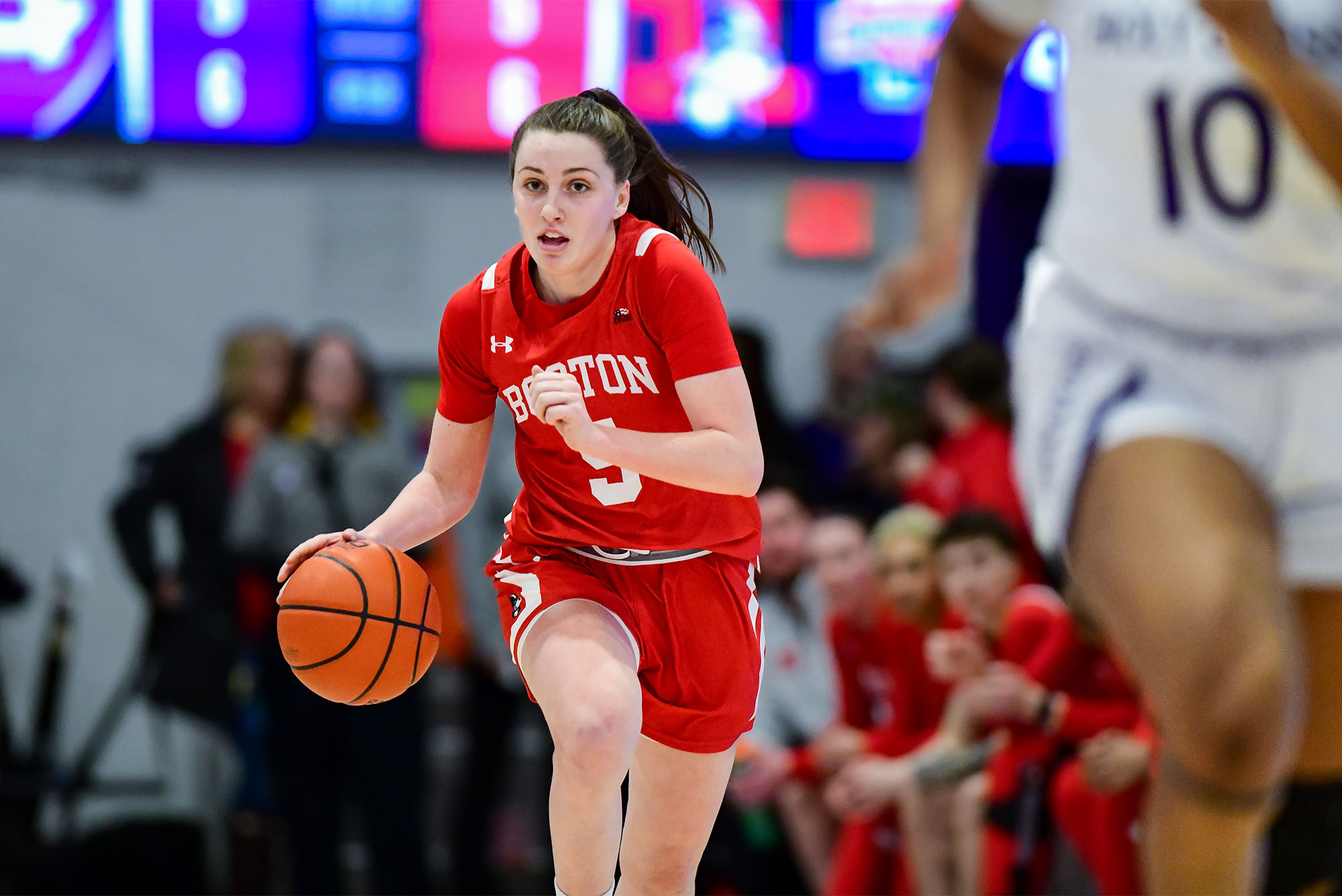 Photo: A Boston University women's basketball player dribbles down the court during a recent game in a red jersey with white trim