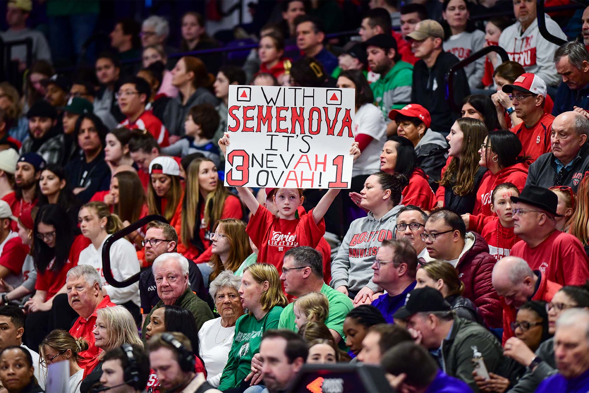 Photo: A young fan holding a sign in a sea of fans at a women's basketball game. The sign reads "With Semenova, it's 'neva ovah' [never over]"