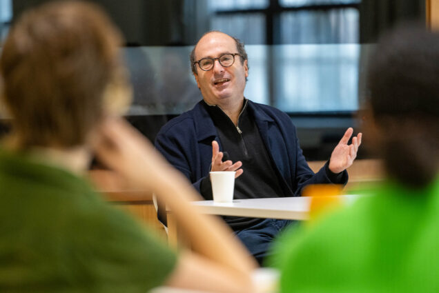 Photo: David Grann, a white man with balding hair, gestures as he speaks to a crowd of BU students for BU's discussion at Kilachand Hall Commons Room