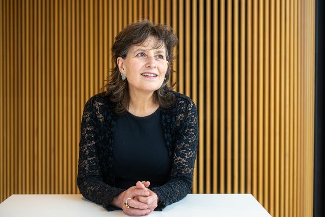 Photo: A woman with a smile on her face wearing a black shirt in front of a vertically slatted background