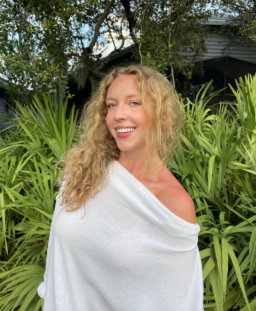 Boston University student Patricia Rueckert (Sargent ‘25). She is in front of greenery, with her blonde curly hair down, smiling at the camera. 