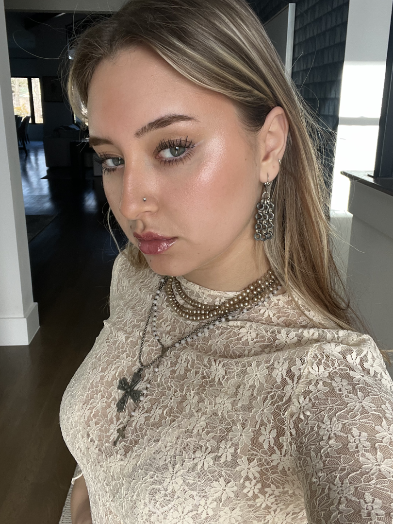 Boston University student Marianna Torres (COM ‘24). This is a selfie of her looking at the camera with a straight face on. She is wearing a white floral top with jewelry on.