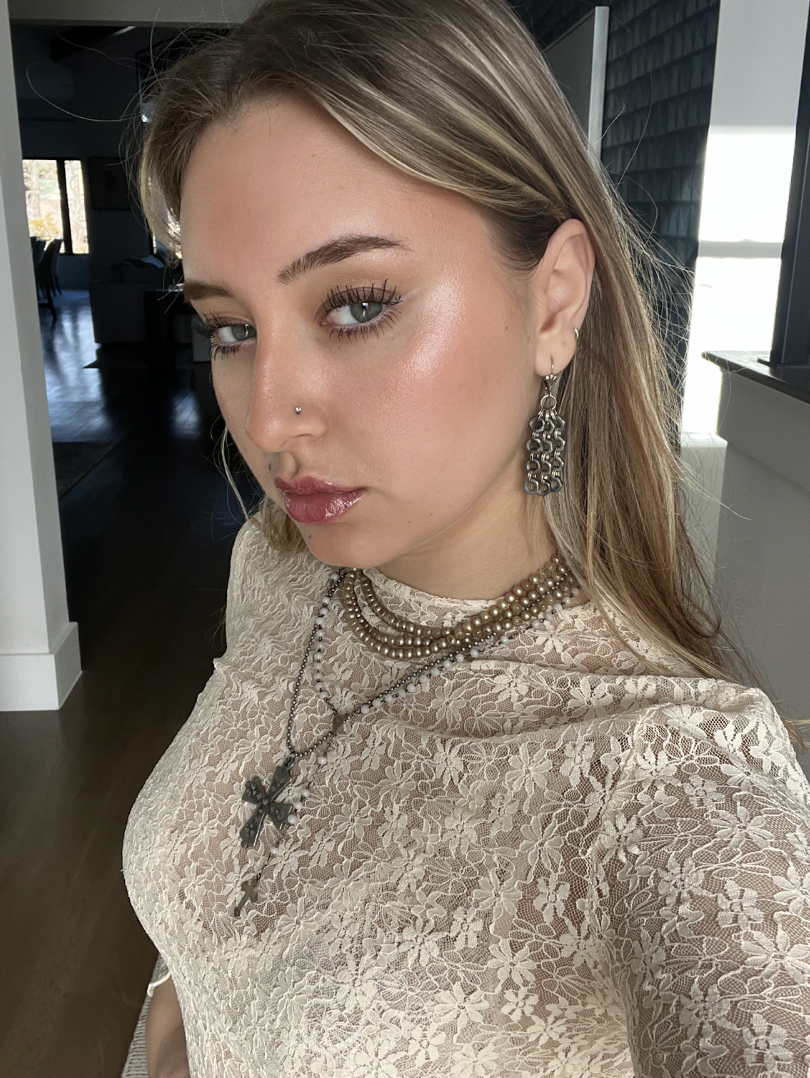 Boston University student Marianna Torres (COM ‘24). This is a selfie of her looking at the camera with a straight face on. She is wearing a white floral top with jewelry on. 