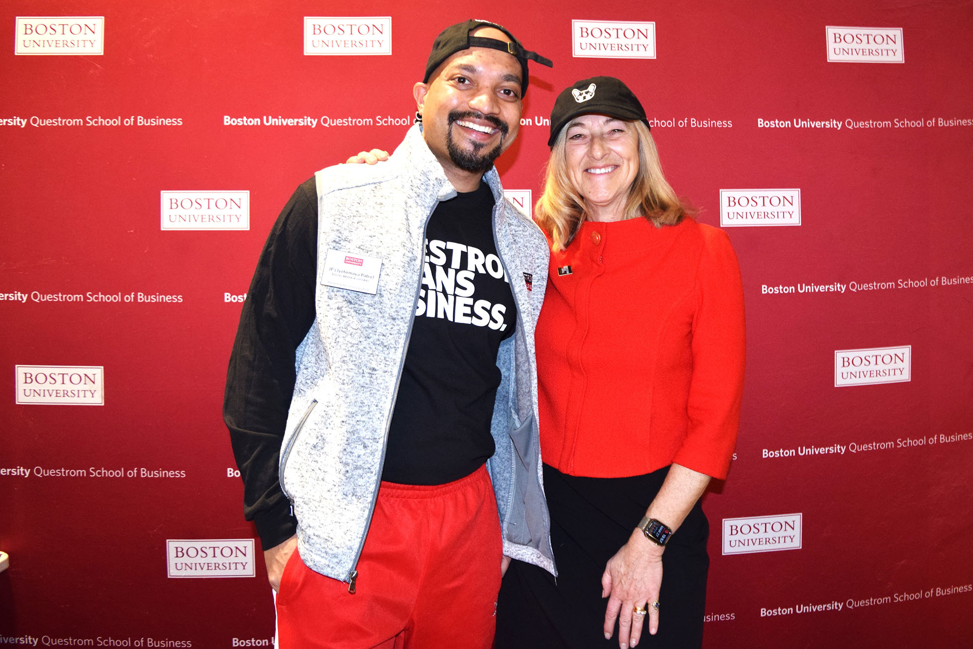 Photo: A picture of a man and a woman smiling and posing for a picture. They are in front of a red background with the "Boston University" logo