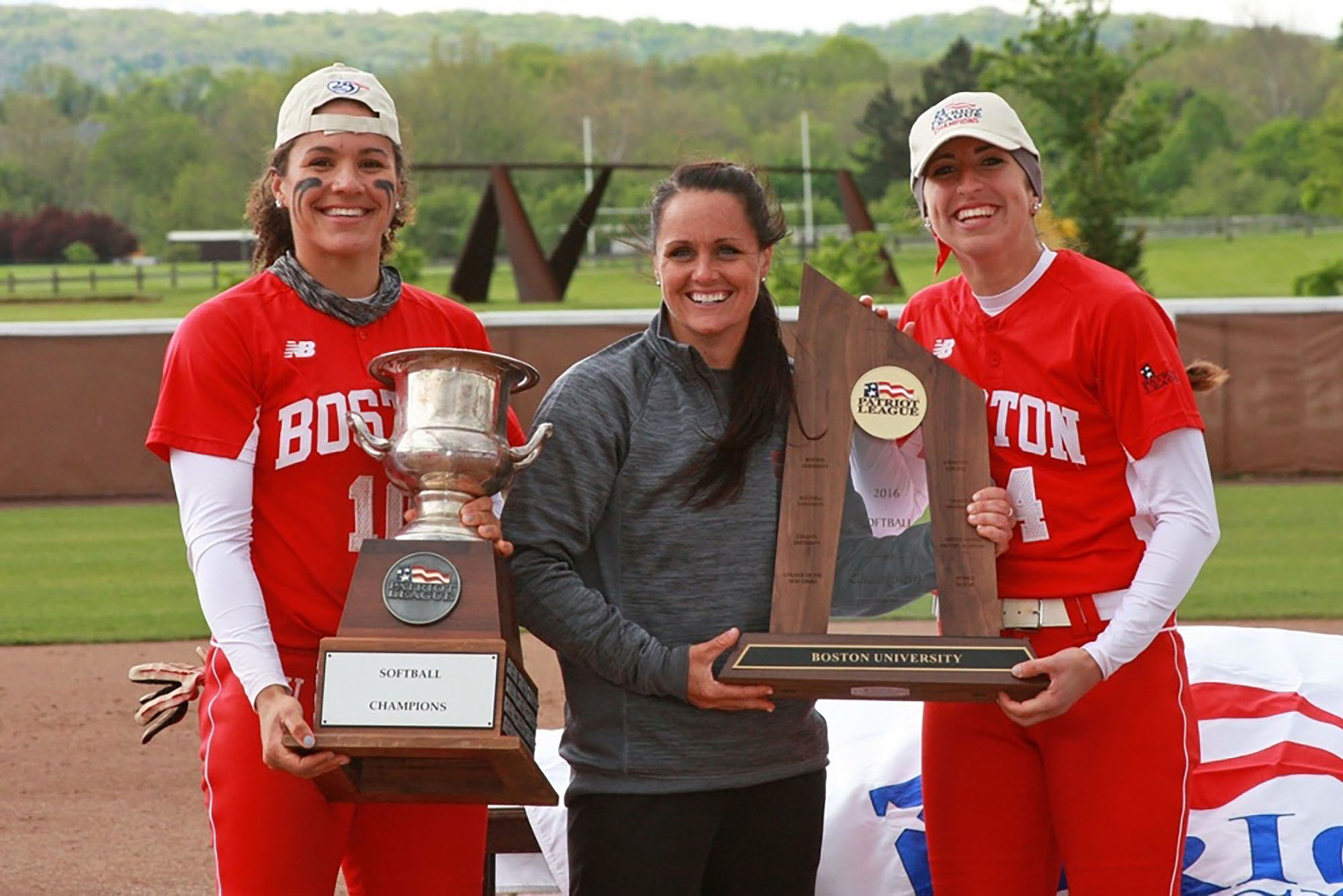 Photo: Ashley Waters, middle, with her two players holding two large trophies. They are all smiling at the camera.