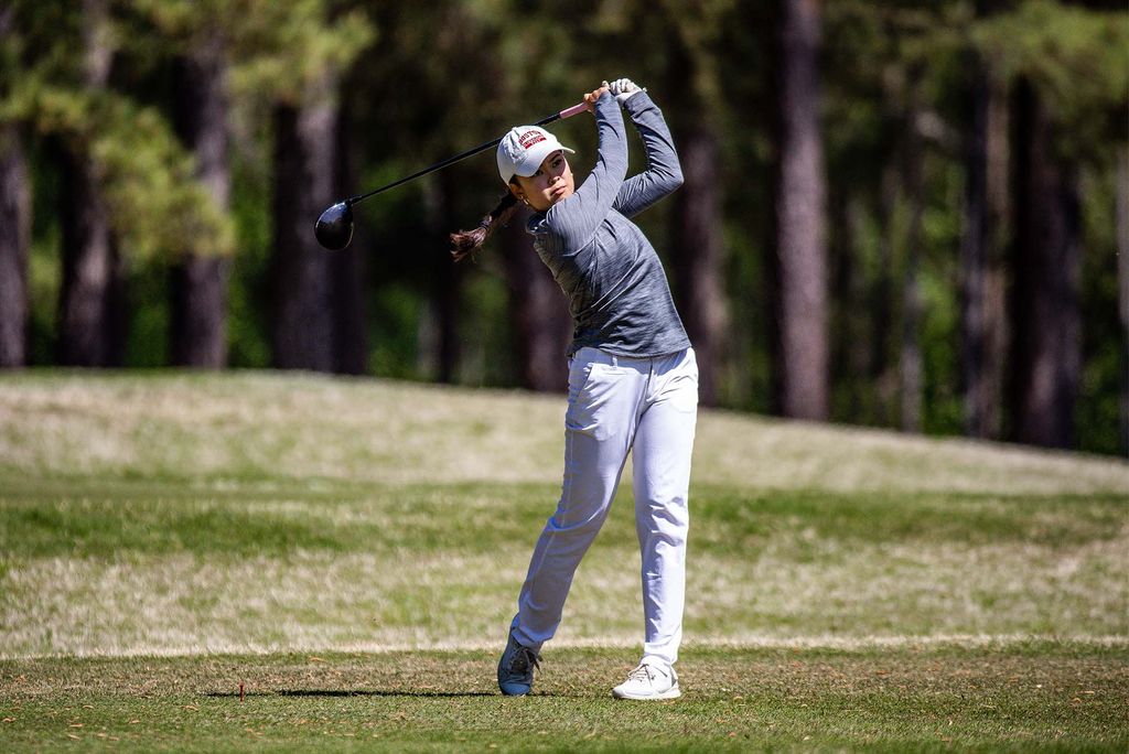 Photo: A college student mid gold swing at a recent Women's golf meet