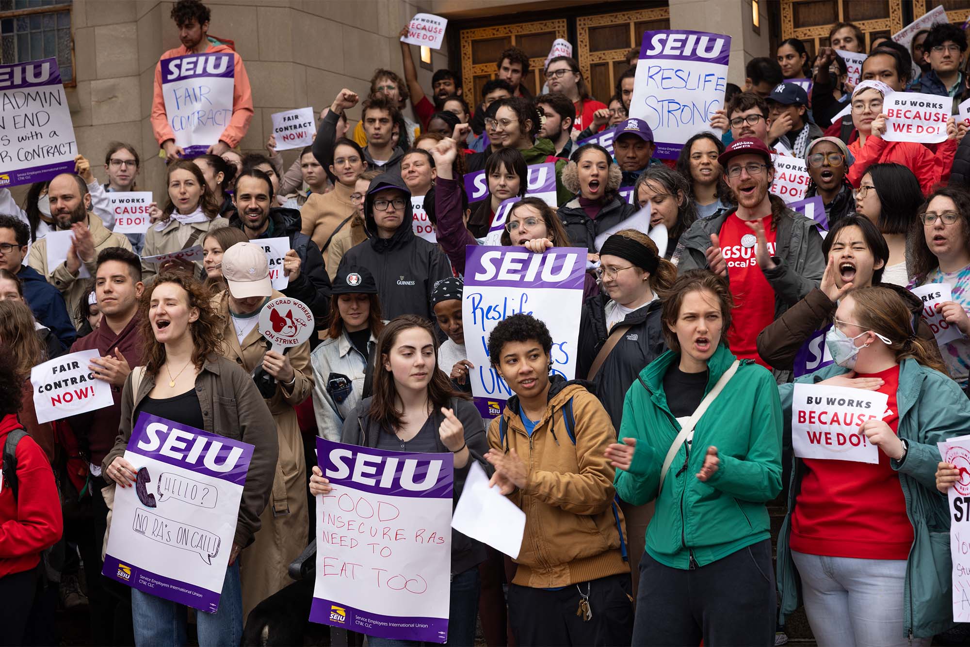 Photo: A large group of striking Residence Assistants at Boston University holding picket signs on Marsh Plaza
