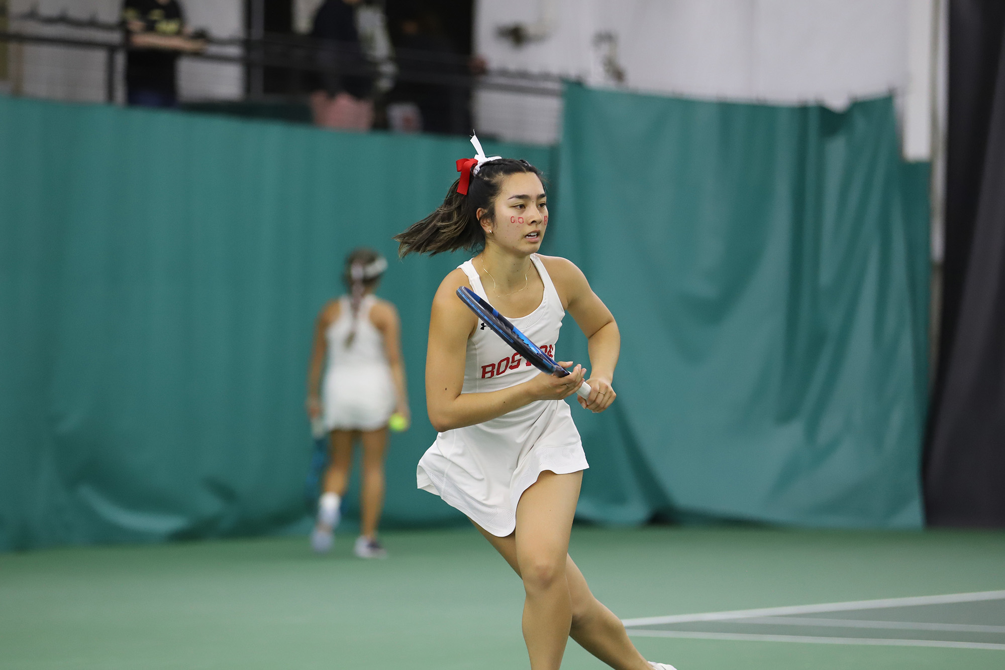 Photo: A women's tennis player in a white outfit runs towards the ball in a recent match, with racquet in hand