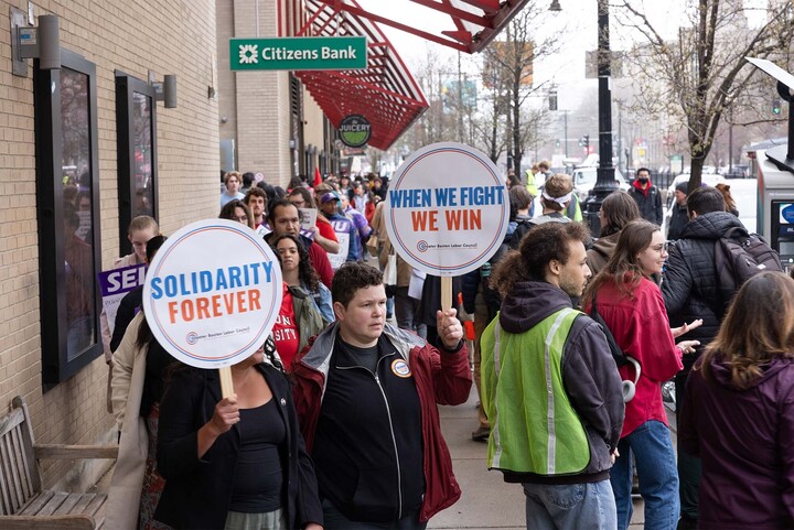 Photo: A group of BU RA strike outside on BU's campus. They hold up picket signs that read SOLIDARITY FOREVER.