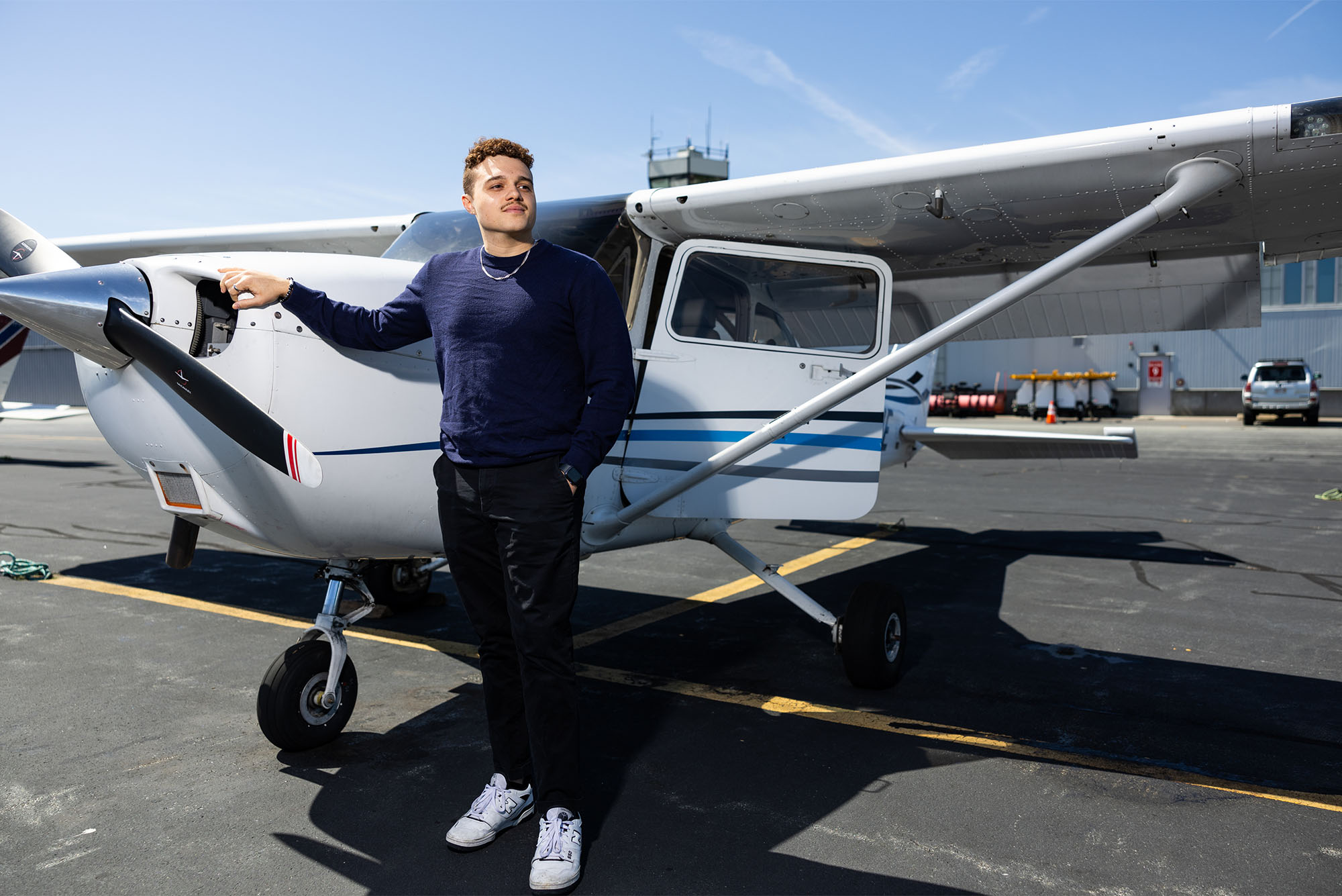 Photo: A young man standing in front of a small Cessna plane