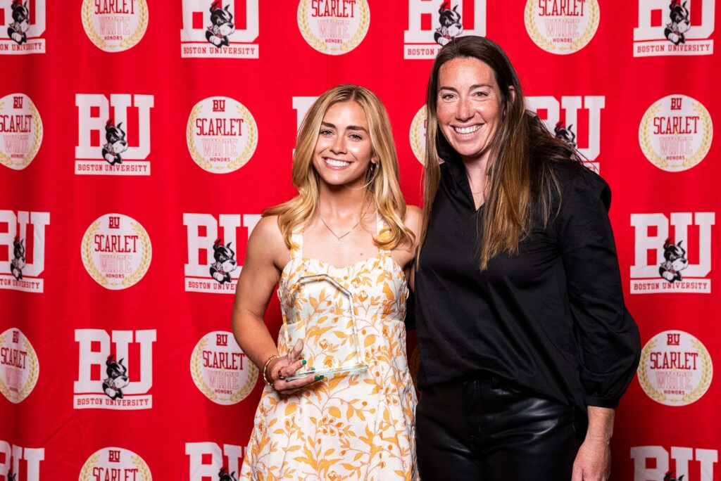 Photo: A picture of two people posing with a clear award in front of a red background that says "BU"