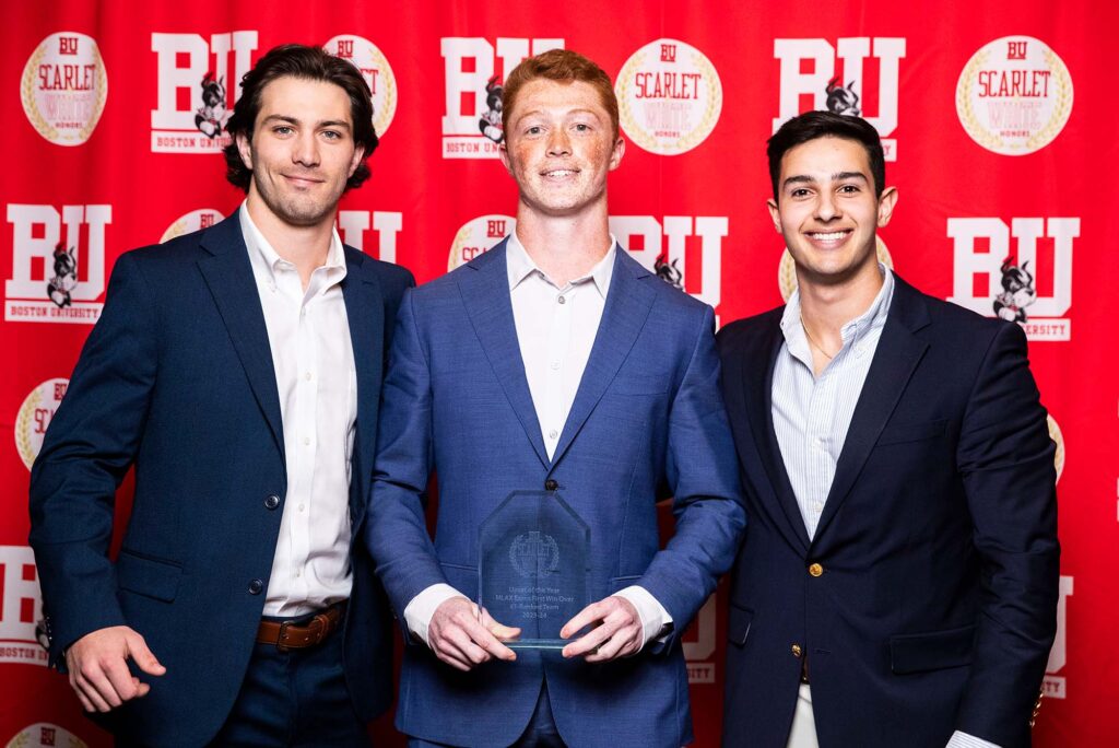 Photo: A picture of three men in suits posing with a clear award. There is a red background that says "BU" behind them