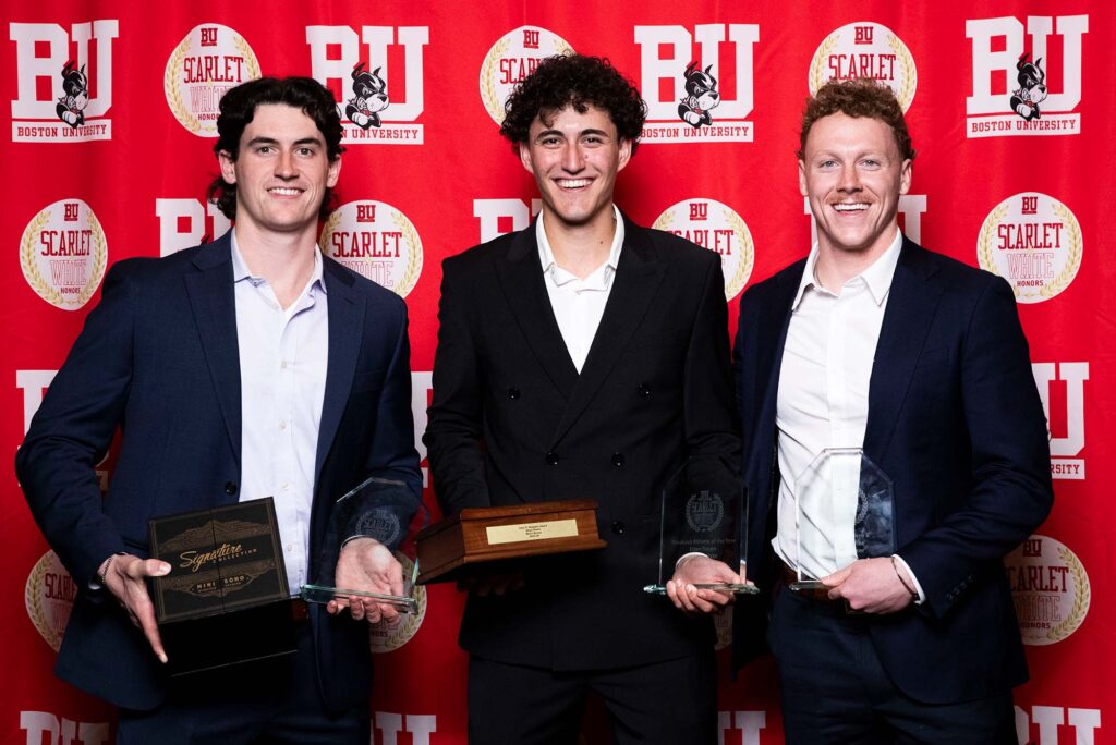 Photo: A picture of three men posing with awards. There is a red background that says "BU" behind them