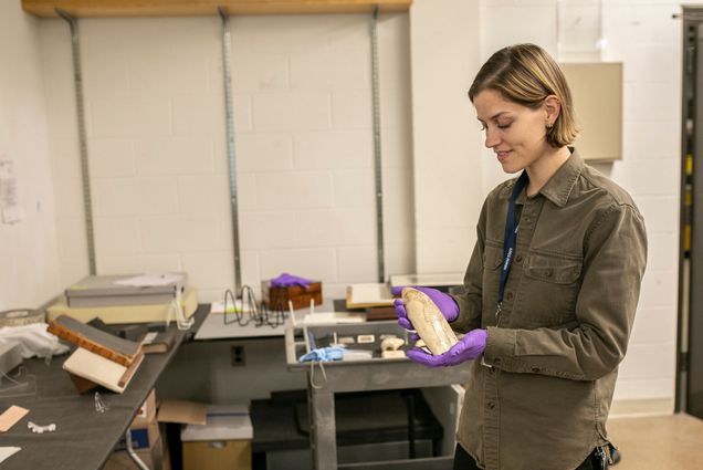 Marina Dawn Wells (GRS’20,’24) examining a scrimshaw carving of a trans pirate, "Alwilda," that a whaleman copied out of a book by Charles Ellms, The Pirates Own Book (1837). Photo by Drew Furtado, New Bedford Whaling Museum