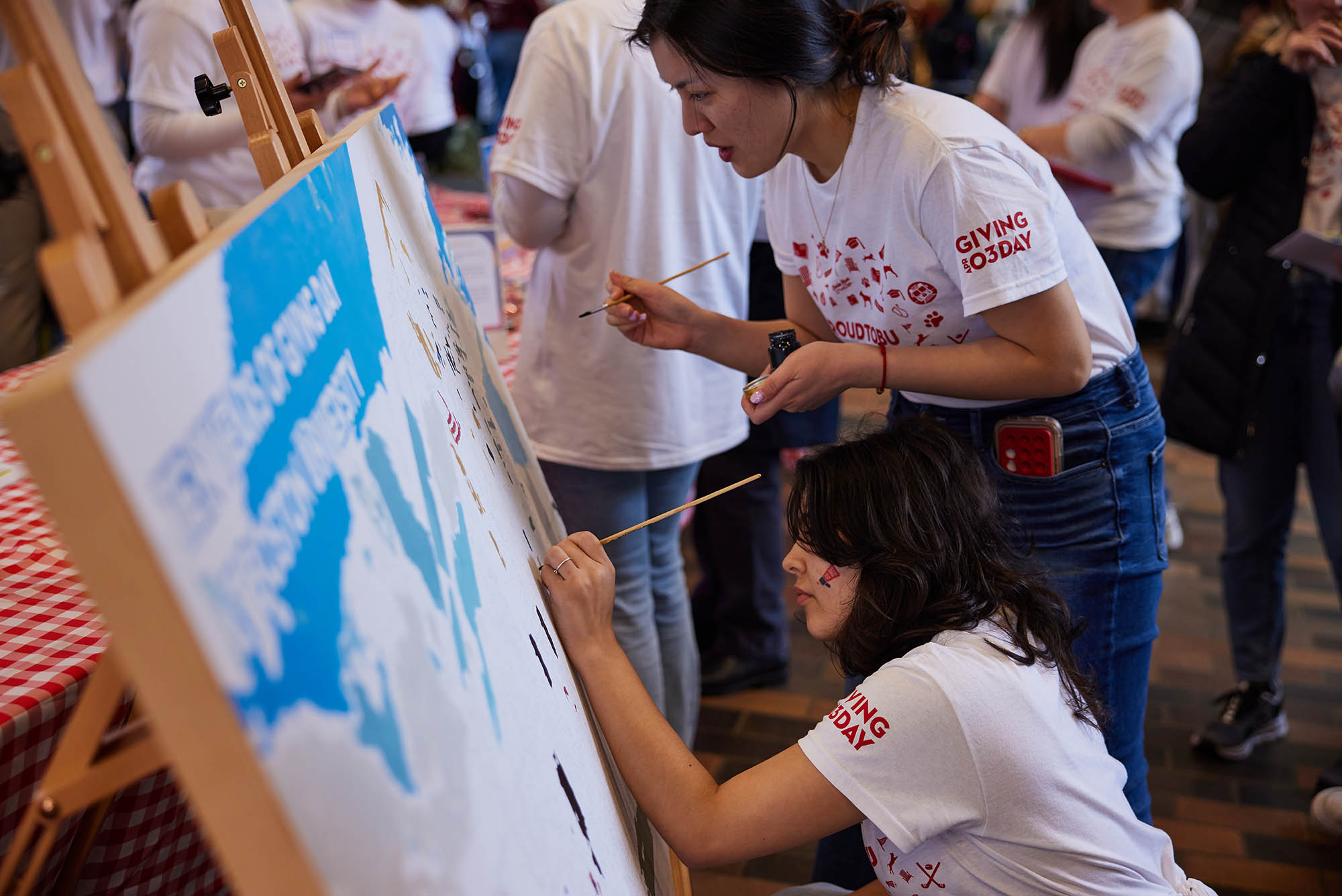 Photo: Students write and add to a mural--a big canvas--for Giving Day.