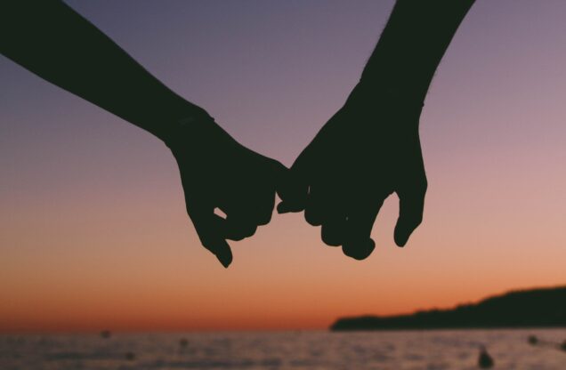 people holding hands in front of a sunset. There hands appear as a sillhouette. Photo courtesy of Canva.com