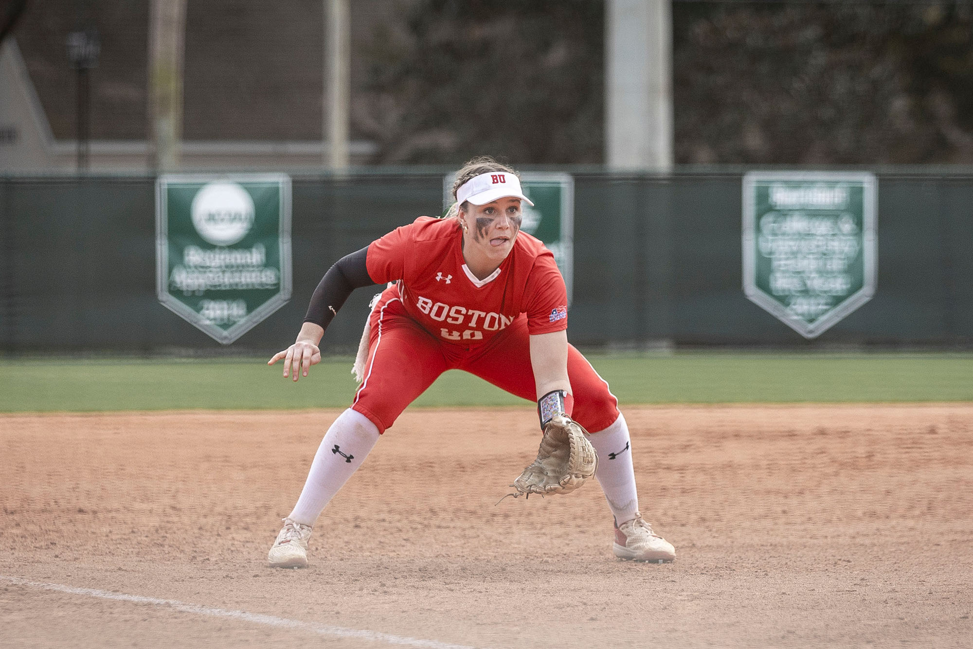 Photo: A softball player on the field. She is wearing a red uniform with white accents