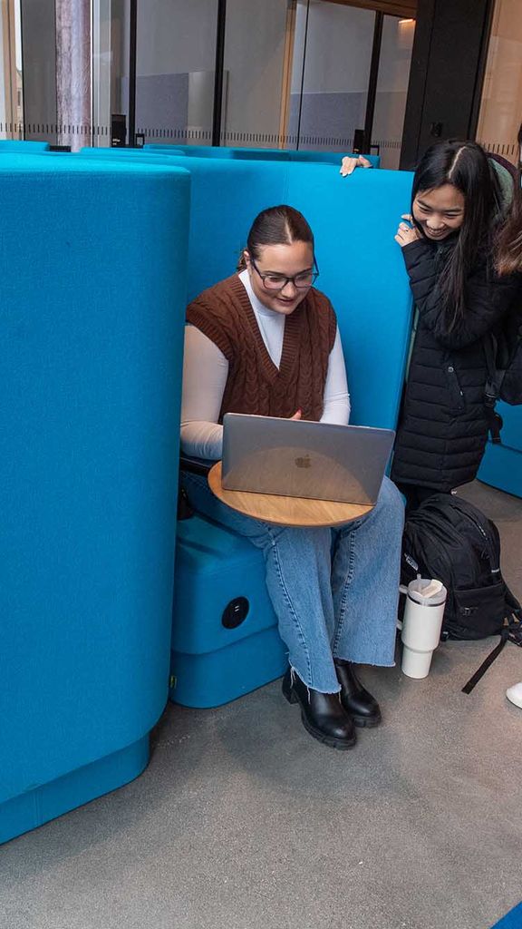 Photo: Becky Geisberg (CAS’26), center from left, Ella Hain (CAS’26), and Amelia Liston (CAS’26) chat for bit at SPARK on the second floor of the Center for Computing & Data Sciences. They sit on the computer in blue chairs and on their laptop.