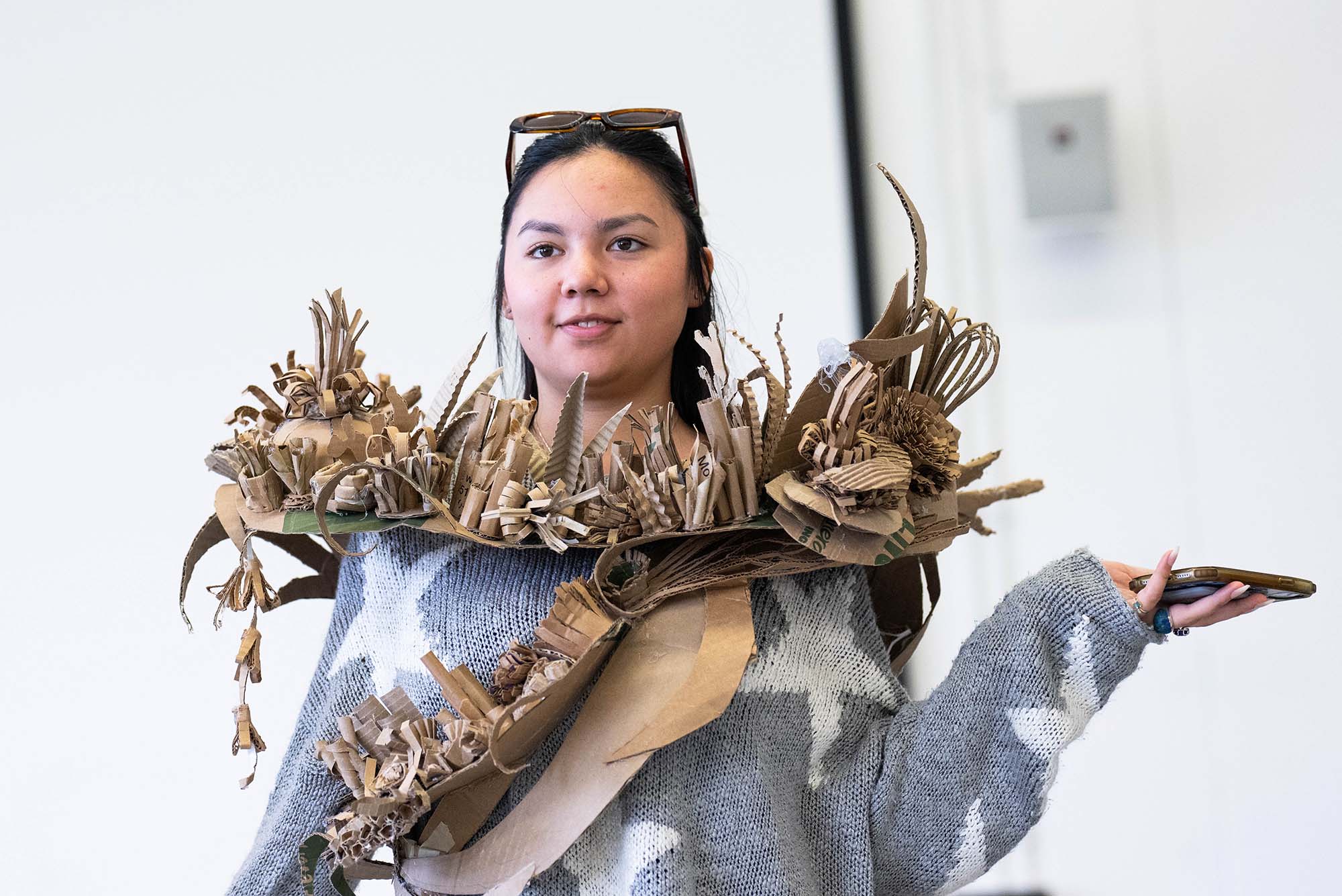 Photo: A picture of a girl wearing a gray sweater with white stars and a cardboard sculpture around her neck. The sculpture sits almost like a scarf and features 3D elements