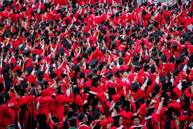 Photo: A sea of Boston University graduates in red gowns sit on Nickerson Field at the 151st Commencement in 2024