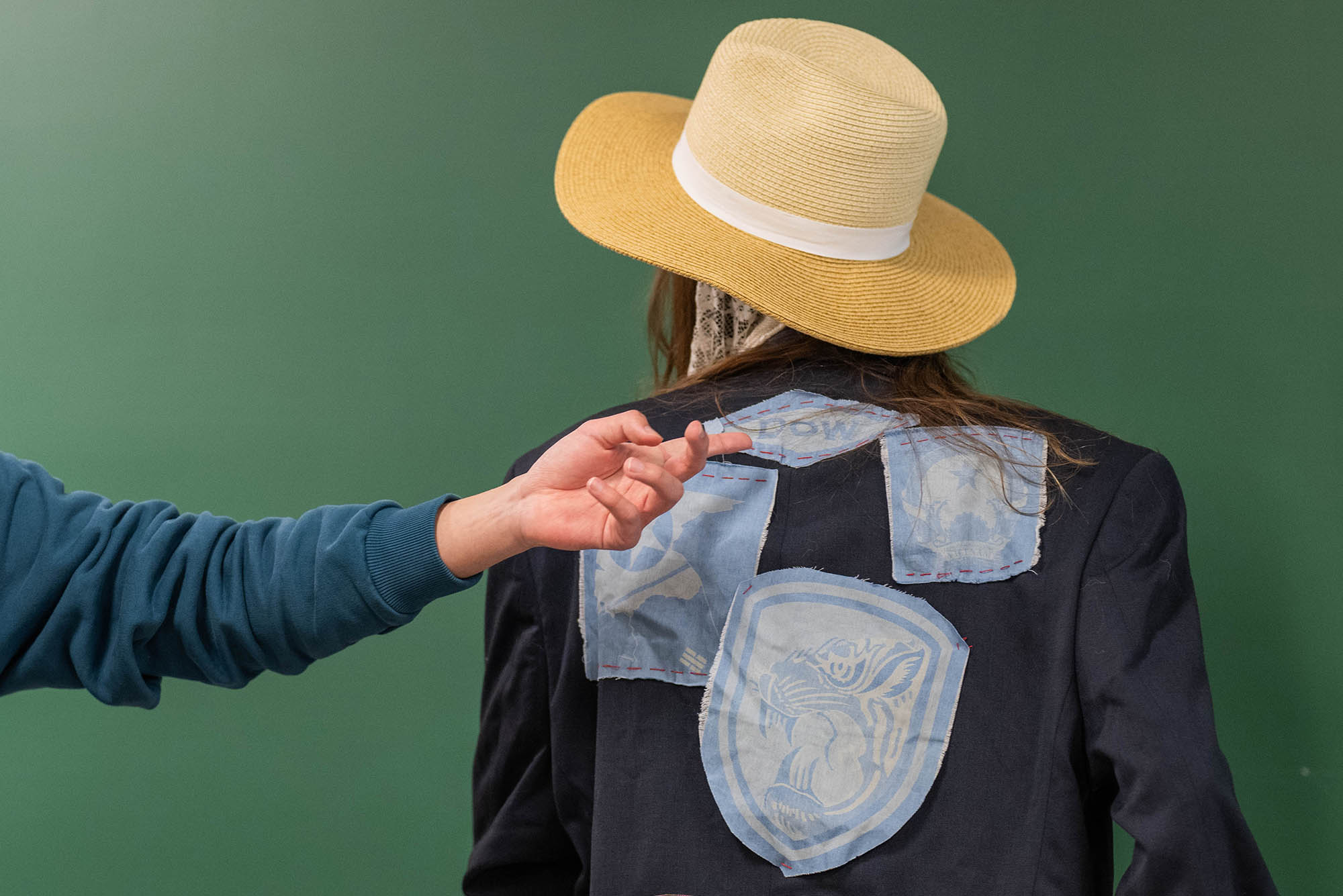 Photo: Photo of student in Jilene Chua's class modeling their creation for the course. A jacket with blue patches on the back.