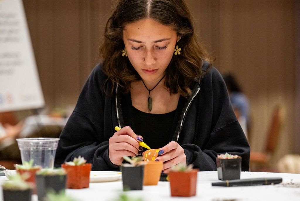 Photo: A picture of a woman painting a small pot for a plant