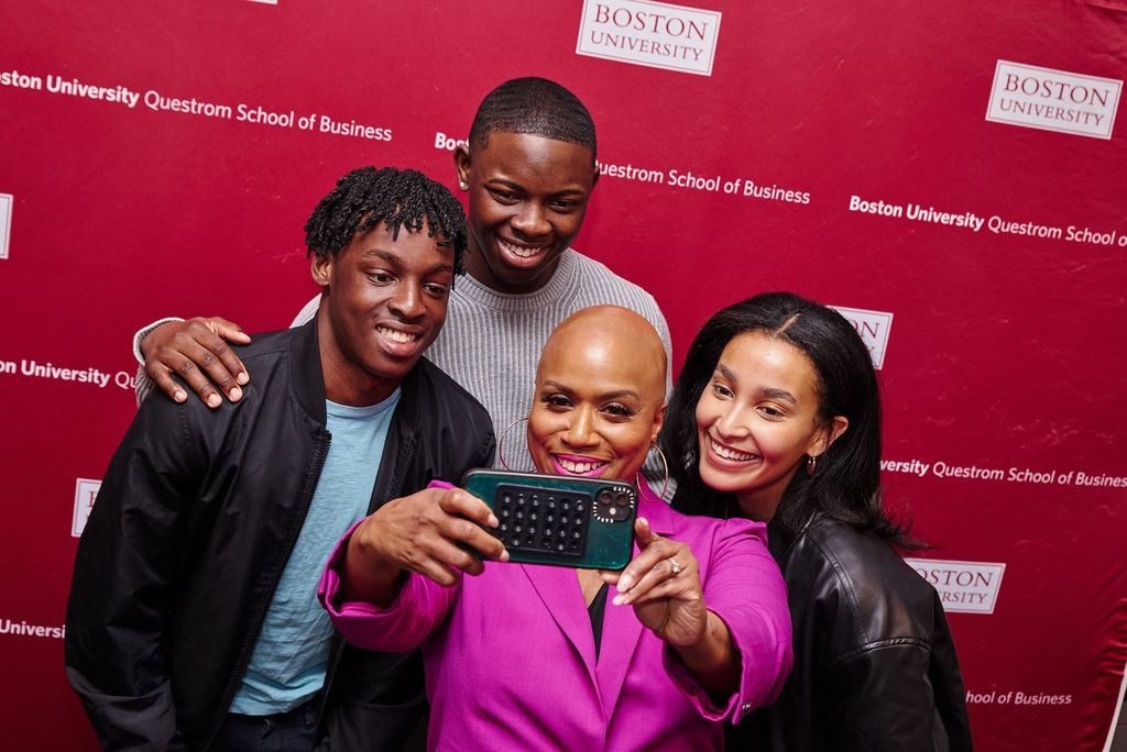 Photo: A picture of a woman in a pink suit taking a selfie with three people