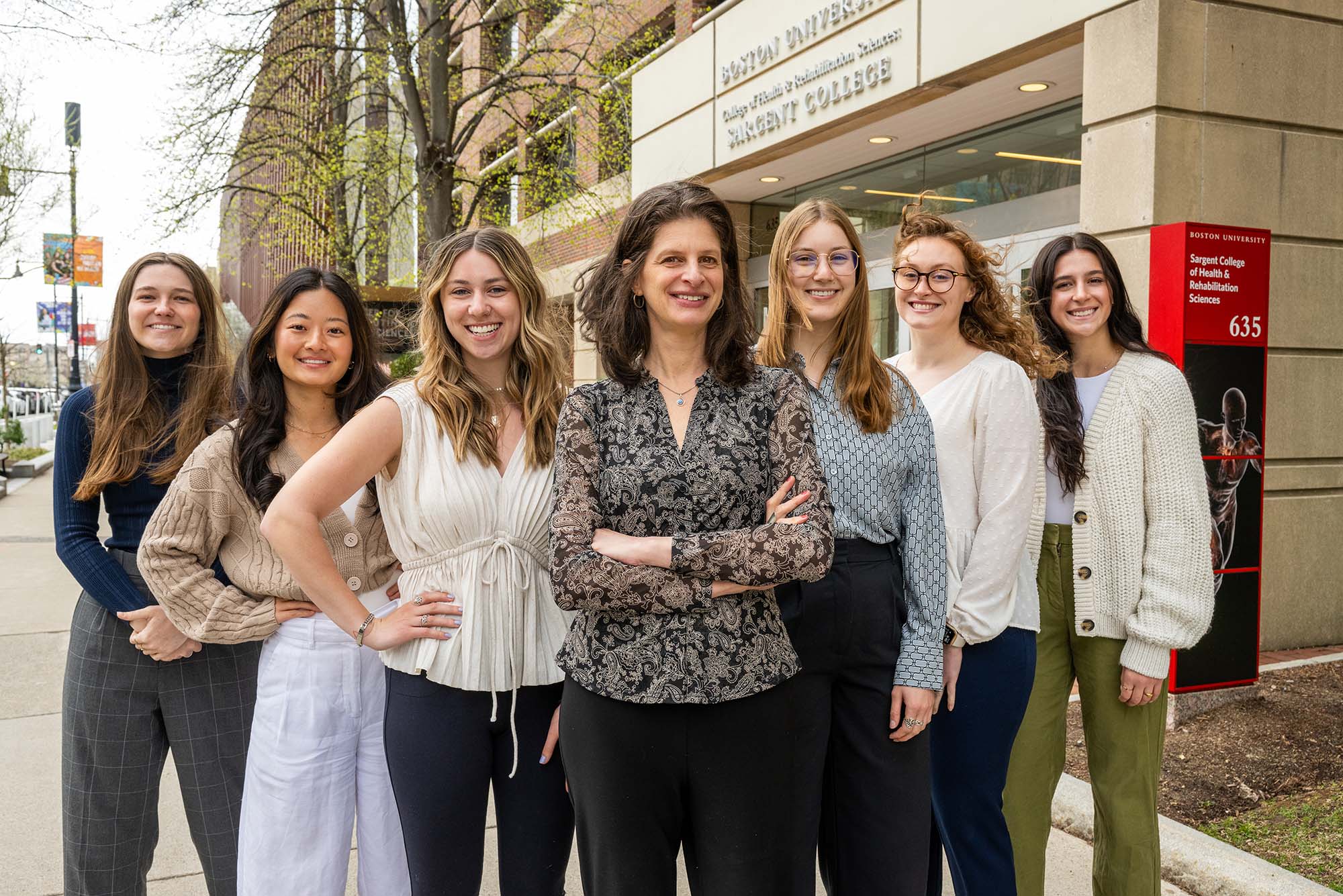 Photo: A photo of seven women posing outside of a building that says "Boston University Sargent College"