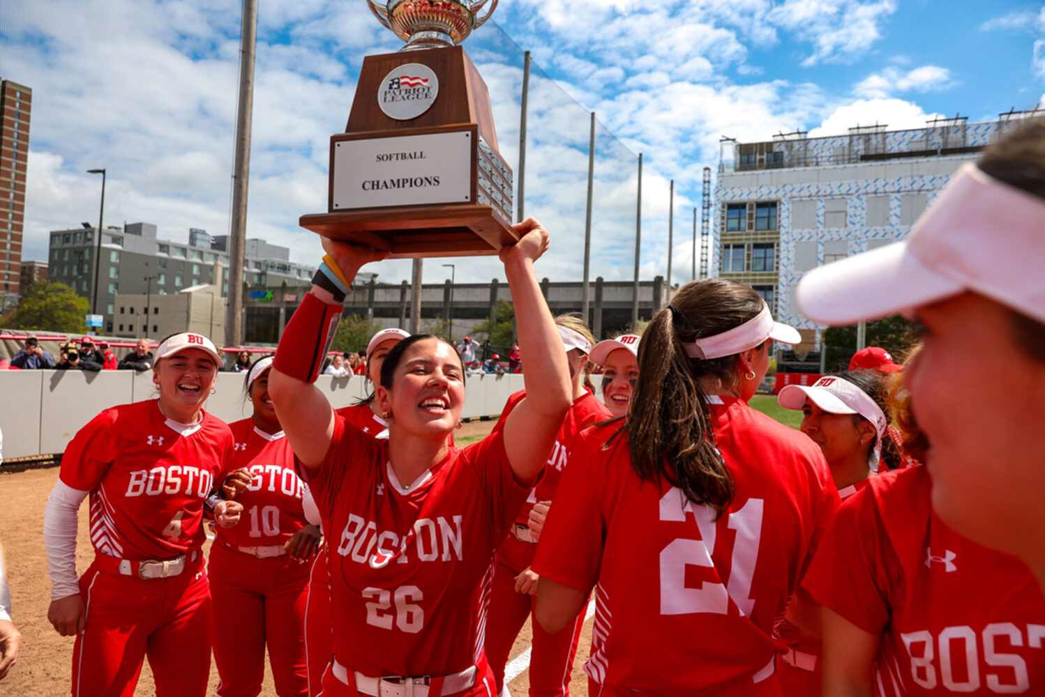 Photo: A picture of a girl in a softball uniform holding a trophy over her and her teammates' heads