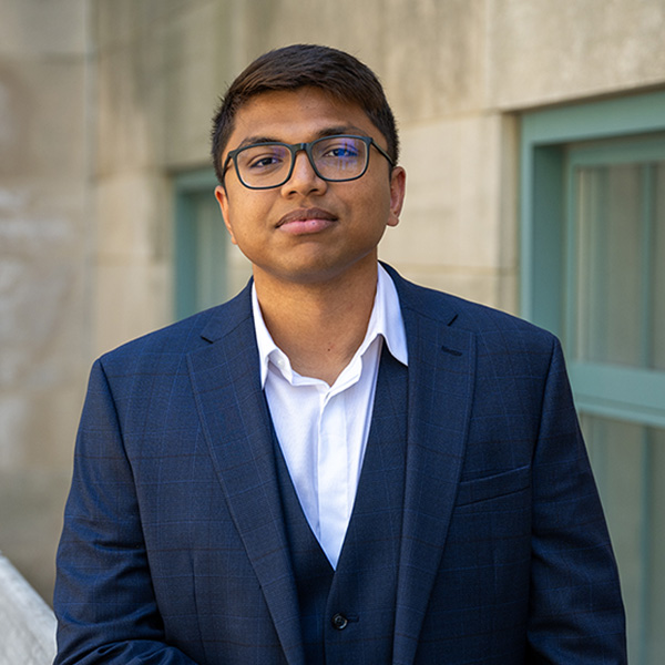 Photo: A college graduate wearing a navy suit and glasses with a collared white shirt