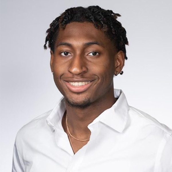 Photo: A black male college student smiles in a formal portrait wearing a white collared shirt