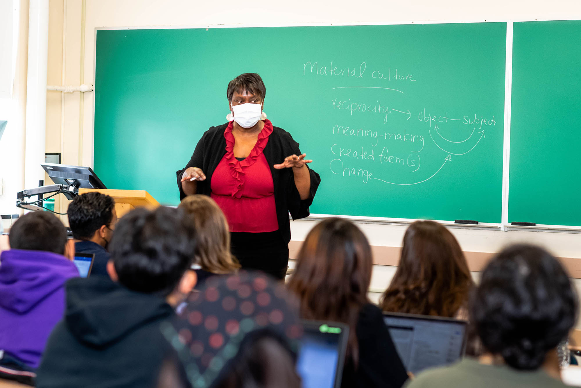 Photo: Professor Margarita Guillory, a Black women with short hair, a red shirt, and a black cardigan, teaches a HipHop and Religion class at CAS