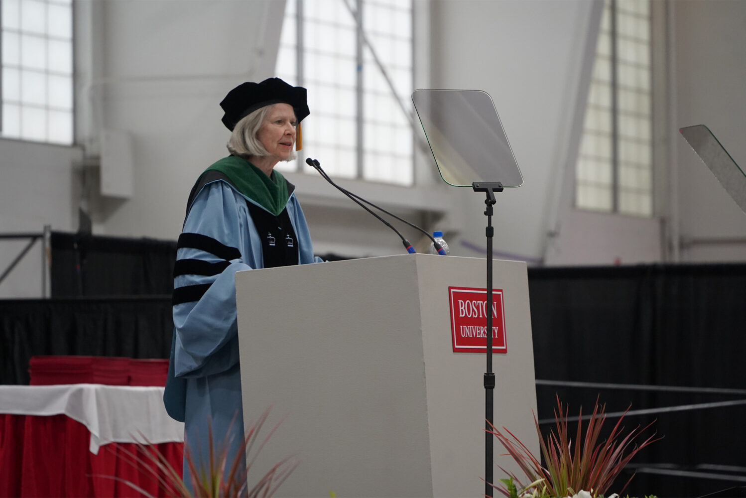 Photo: Karen Antman, a woman wearing formal attire stands at a podium at Boston University's 2024 commencement