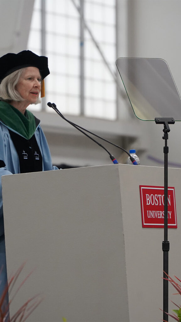 Photo: Karen Antman, a woman wearing formal attire stands at a podium at Boston University's 2024 commencement
