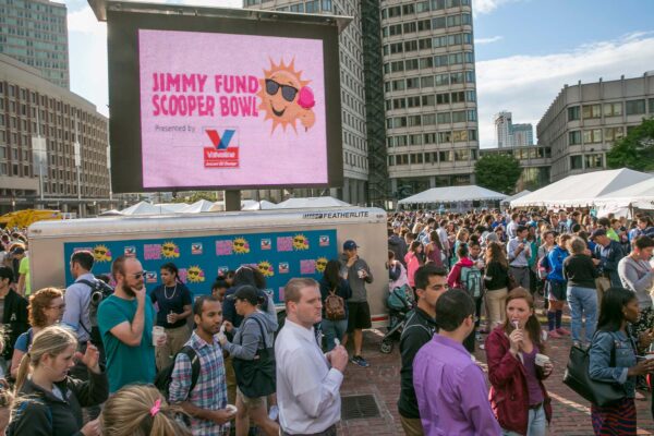 Photo: A picture of an outdoor ice cream event. A large screen says "Jimmy Fund Scooper Bowl"