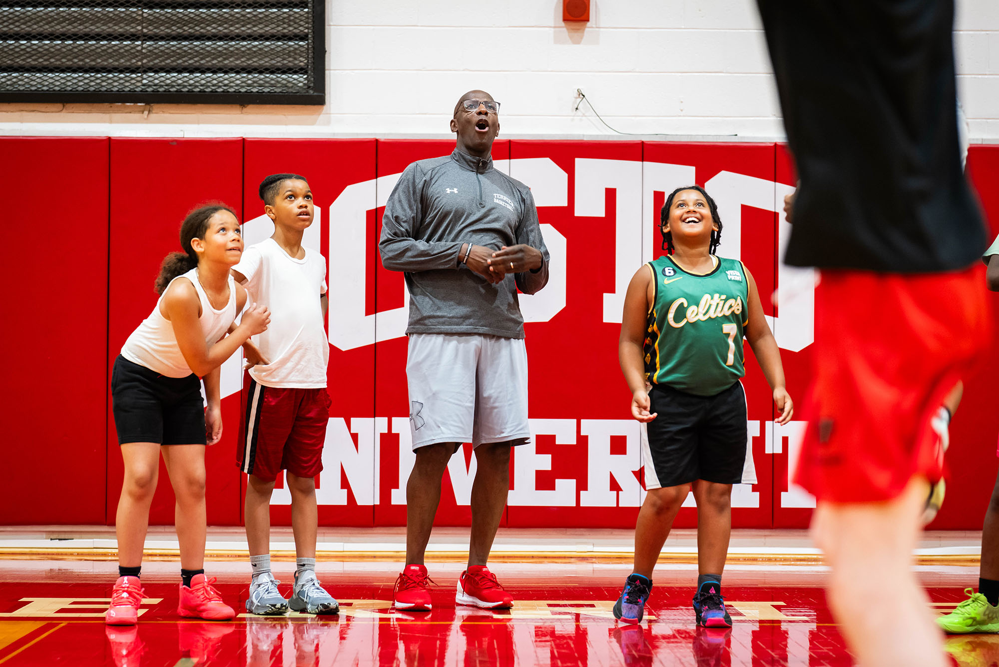 Photo: A picture of BU men's basketball coach Joe Jones and students from Boston elementary schools on the court