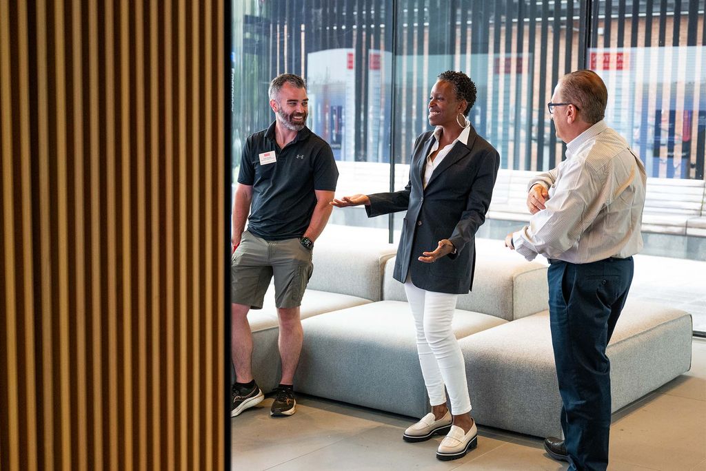 Photo: Two men in conversation with BU president Melissa Gilliam in a room with a modern wood design