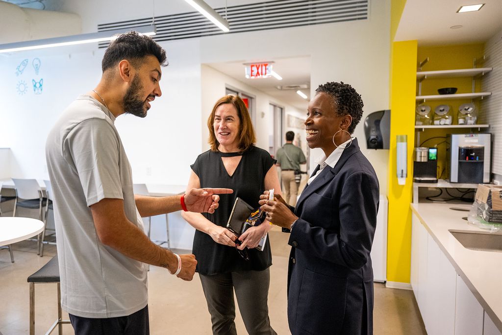 Photo: A tall man greets president Melissa Gilliam with excited conversation