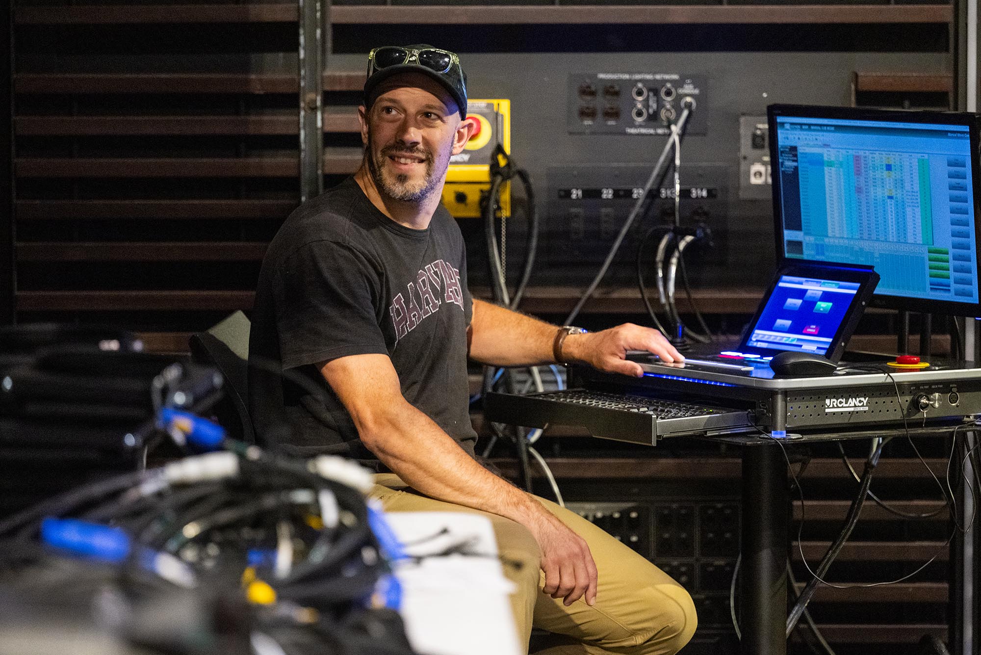 Photo: Dan Jensen, a white man with a gray tshirt and a black cap, in Booth Theater