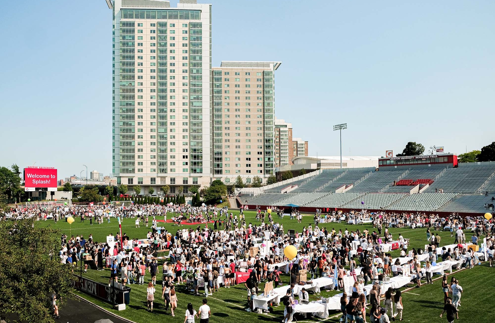 Photo: A large group of students standing on a soccer field in front of a large skyscraper